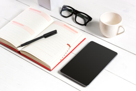 Stylish minimalistic workplace with tablet and notebook and glasses in flat lay style. White background
